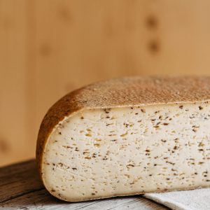 Halbierter Lungauer Schnittkäse mit Kümmel auf Holztisch, regionale Spezialität aus Salzburg