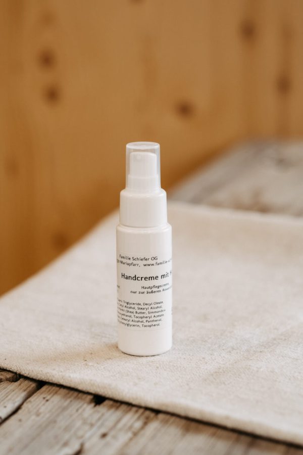 Weiße Flasche Handcreme aus dem Lungau auf Holz- und Stoffuntergrund, regionale Spezialität
