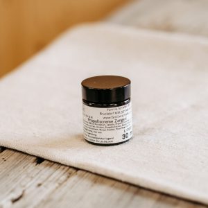 Glas mit Propoliscreme aus regionaler Lungauer Produktion auf Holztisch im Hofladen