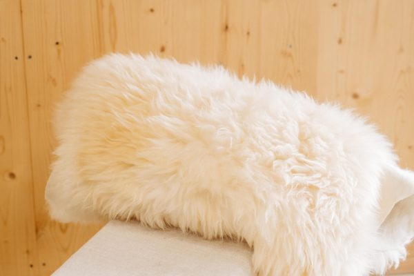Natürliches, flauschiges Schaffell aus dem Lungau vor hellem Holz, regionale Spezialität