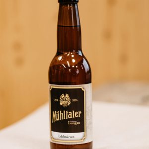 Braune Bierflasche Mühltaler Edelmärzen auf Holz und weißer Serviette, regionale Spezialität Lungau