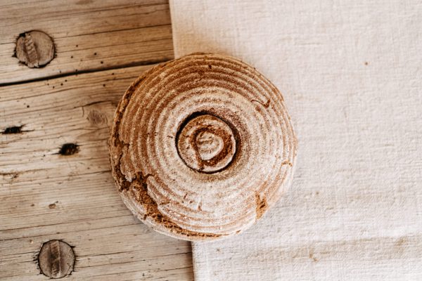 Rundes Bauernbrot aus dem Lungau auf rustikalem Holztisch, regionale Spezialität Hofladen