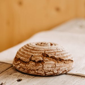 Rustikales rundes Bauernbrot aus dem Lungau auf Holzbrett, regionale Spezialität