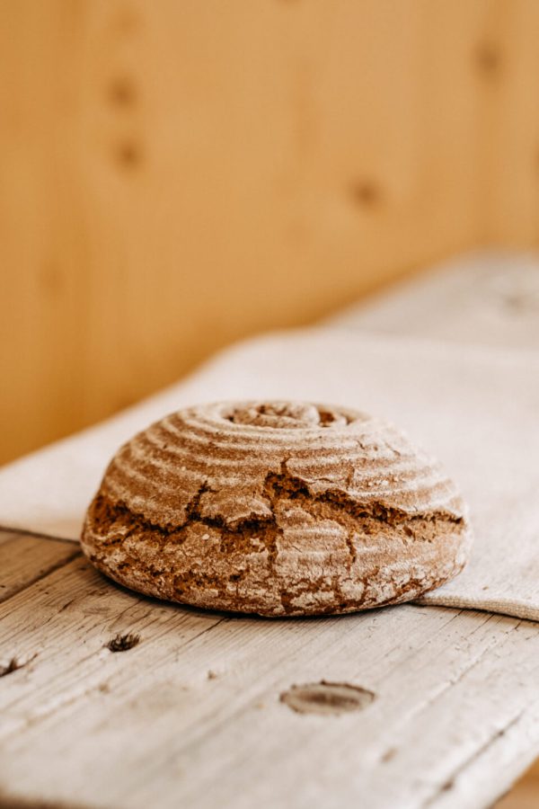 Rustikales rundes Bauernbrot aus dem Lungau auf Holzbrett, regionale Spezialität