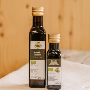 Zwei Flaschen Bio-Hanföl aus Lungau, kaltgepresst, regional produziert auf Holztisch