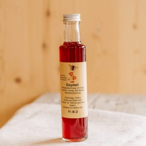 Flasche Oxymel mit Heidelbeerextrakt auf Holzbrett, regionale Spezialität aus dem Lungau