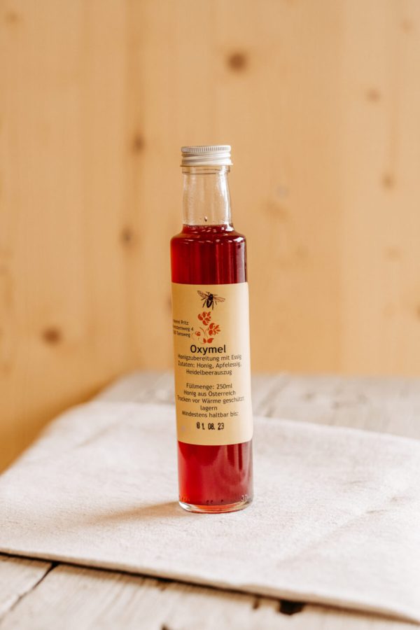 Flasche Oxymel mit Heidelbeerextrakt auf Holzbrett, regionale Spezialität aus dem Lungau
