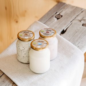 Drei Gläser Bio-Joghurt aus dem Lungau auf rustikalem Holzbrett, regionale Spezialitäten