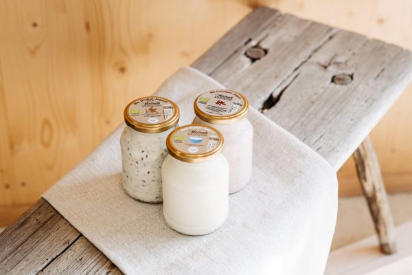Drei Gläser Bio-Joghurt aus dem Lungau auf rustikalem Holzbrett, regionale Spezialitäten