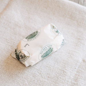 In weißes Papier verpacktes regionales Produkt aus dem Hofladen Lungauer Speis auf Leinentuch