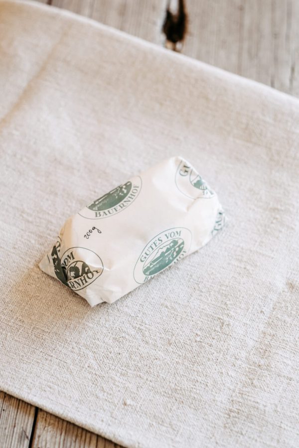 In weißes Papier verpacktes regionales Produkt aus dem Hofladen Lungauer Speis auf Leinentuch