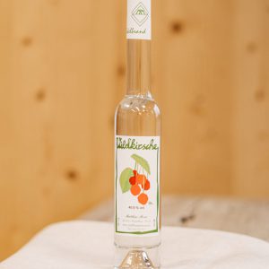 Flasche Wildkirsche-Edelbrand aus dem Lungau, regionale Spezialität auf Holzuntergrund