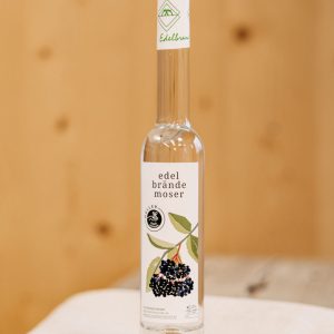Flasche Edelbrand Moser mit Holunder-Label, regionale Spezialität aus dem Lungau auf Holzablage