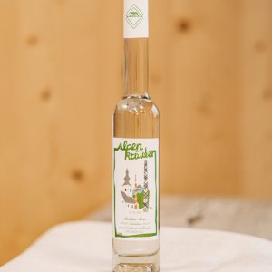 Flasche Alpenkräuter-Schnaps aus dem Lungau auf Holztisch, regionale Spezialität