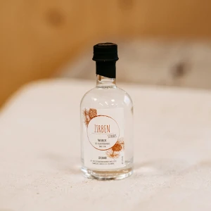 Kleine Flasche Zirbenschnaps aus dem Lungau, regionales Naturprodukt auf Holztisch