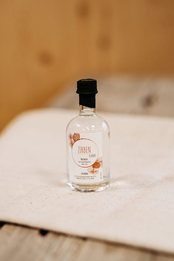 Kleine Flasche Zirbenschnaps aus dem Lungau, regionales Naturprodukt auf Holztisch