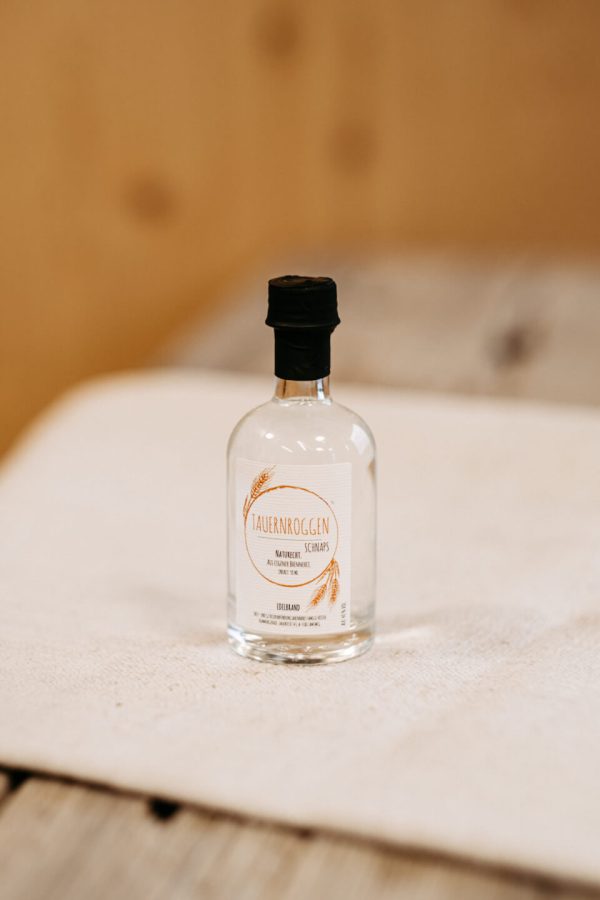 Kleine Flasche Tauernroggen Schnaps aus regionaler Lungauer Landwirtschaft auf Holzuntergrund