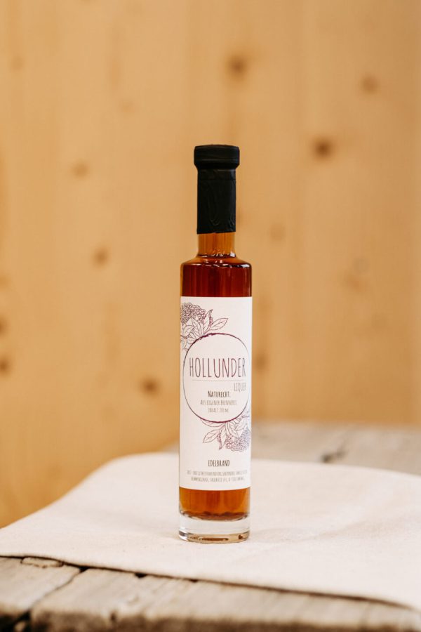 Flasche Hollunder Likör aus dem Lungau, regionales Naturprodukt im Hofladen auf Holztisch