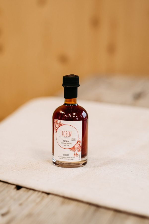 Flasche Rosenlikör aus regionaler Herstellung, Spezialität aus dem Lungau auf Holztisch