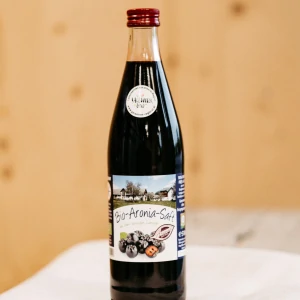 Flasche Bio-Aronia-Saft aus dem Lungau auf Holzuntergrund, regionale Spezialität, Hofladen