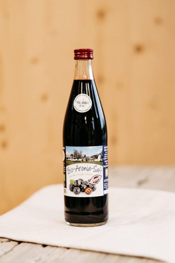 Flasche Bio-Aronia-Saft aus dem Lungau auf Holzuntergrund, regionale Spezialität, Hofladen