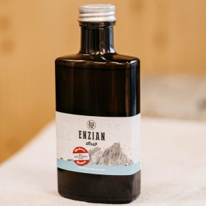 Braune Flasche Enziansirup mit Etikett auf hellem Tuch, regionale Spezialität aus dem Lungau