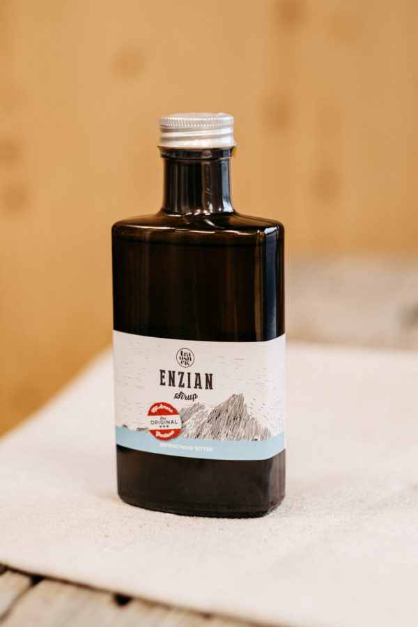 Braune Flasche Enziansirup mit Etikett auf hellem Tuch, regionale Spezialität aus dem Lungau