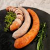 Drei Lungauer Würste mit Kräutern auf schwarzer Platte, regionale Fleischspezialitäten Lungau