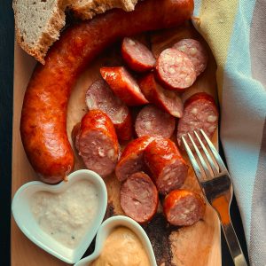 Hausgemachte Wurstscheiben mit Bauernbrot und regionalen Dips auf Holzbrett