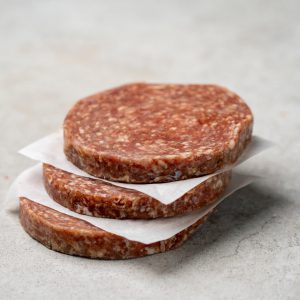 Drei regionale Burgerpatties aus Lungauer Rindfleisch, sauber getrennt, auf hellem Untergrund