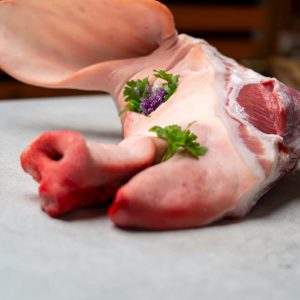 Frisches Schweinekopfstück mit Ohr aus dem Lungau, dekoriert mit Petersilie und Blüte